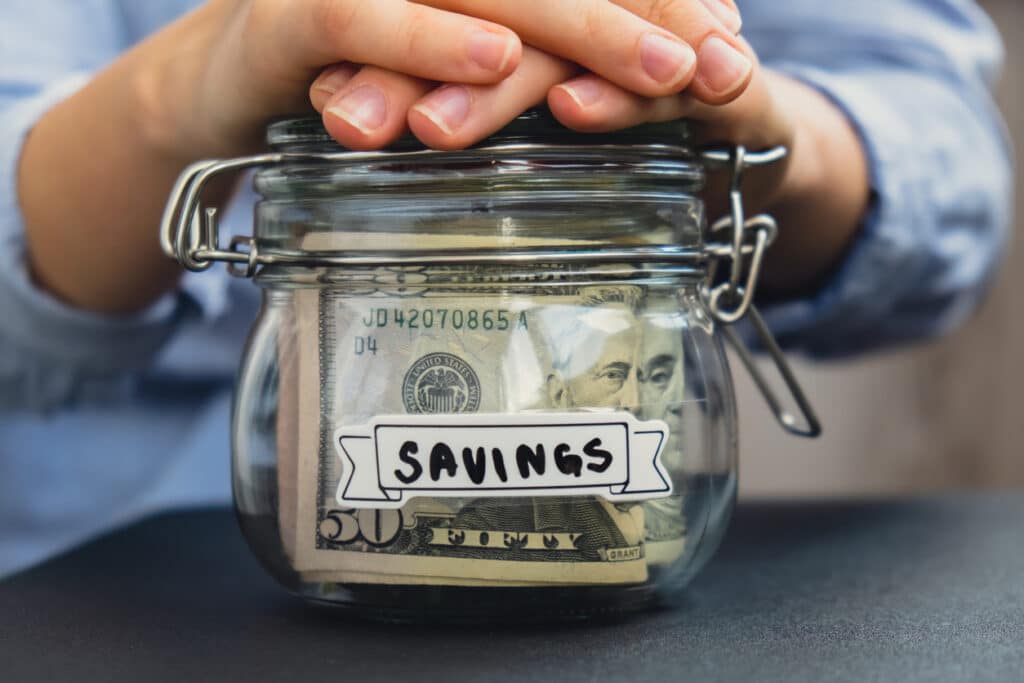 A jar that says "Savings" with cash inside