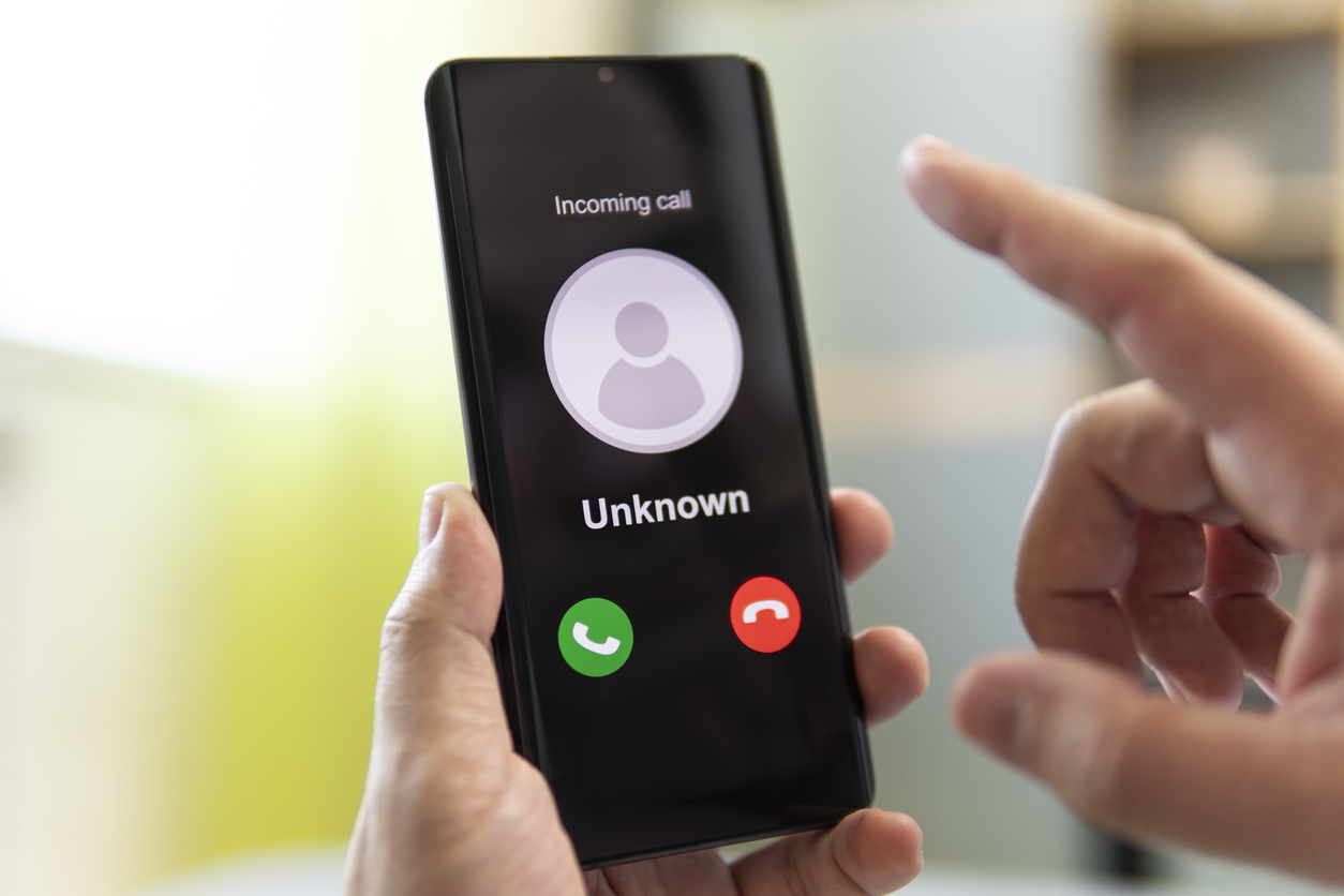 Man holds phone in hand with unknown caller coming in